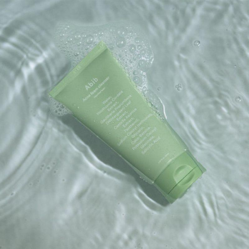 Зелений тюбик Abib Acne Foam лежить на водяній поверхні, навколо нього бульбашки.