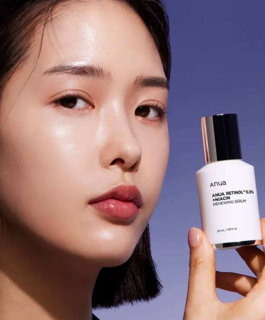 Дівчина азіатської зовнішності тримає пальцями пляшечку засобу Anua Nano Retinol 0,3% + Niacin Renewing.