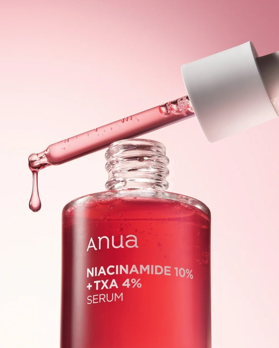 Відкритий флакон сироватки ANUA NIACINAMIDE 10% + TXA 4% SERUM, над ним біла піпетка, з якої витікає червона сироватка на біло-рожевому фоні.