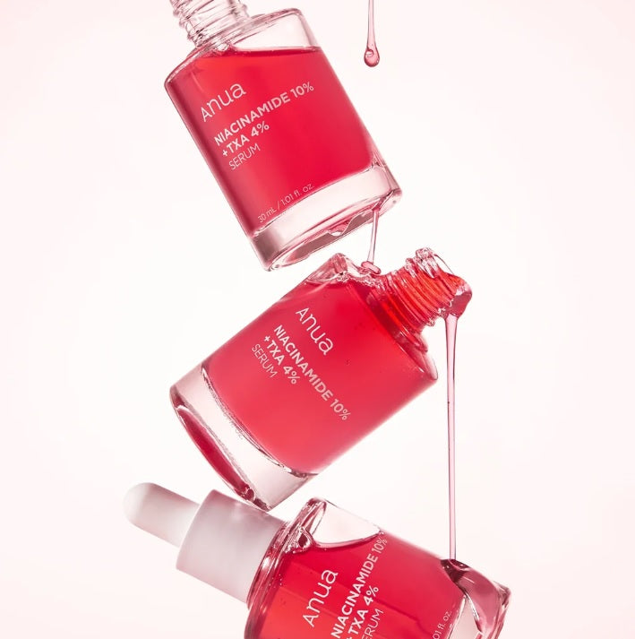 Три флакони сироватки ANUA NIACINAMIDE 10% + TXA 4% SERUM розташовані один над одним під кутом, з двох верхніх флаконів витікає червона сироватка на нижні флакони.