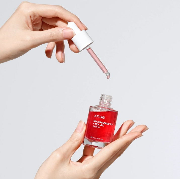 Людина тримає у одній руці відкритий флакон ANUA NIACINAMIDE 10% + TXA 4% SERUM, іншою рукою набирає червону сироватку піпеткою, готуючись до використання.