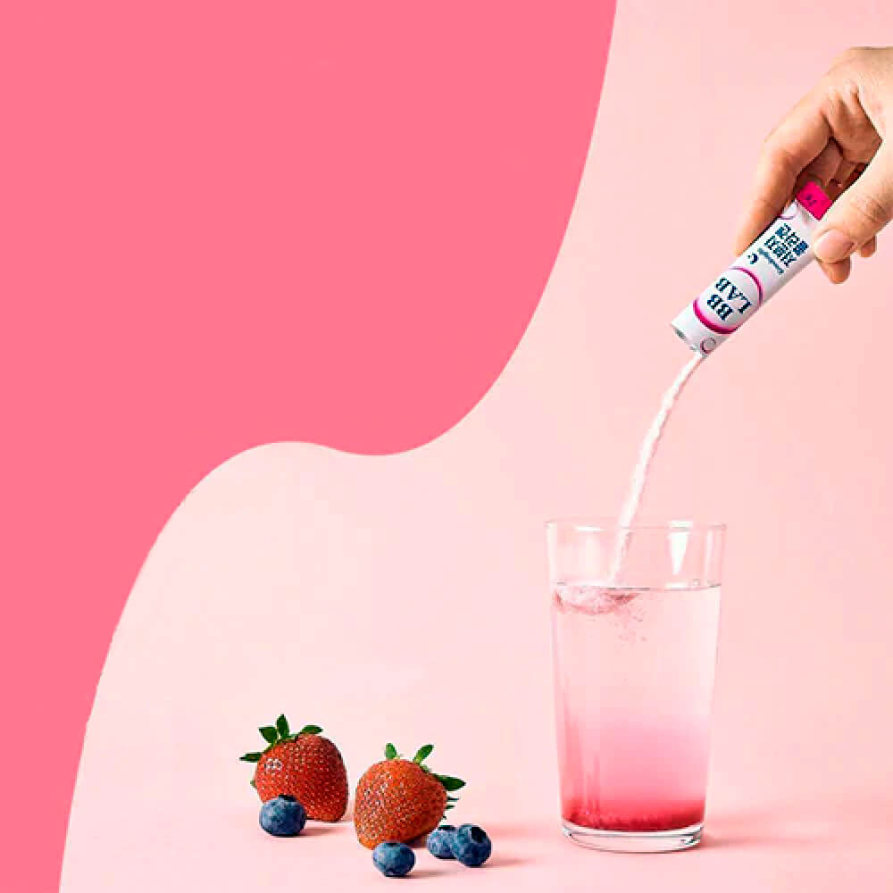 В склянку насипають саше колагену BB Lab Good Night Collagen, поряд лежать полуниця і чорниця, на рожевому фоні.