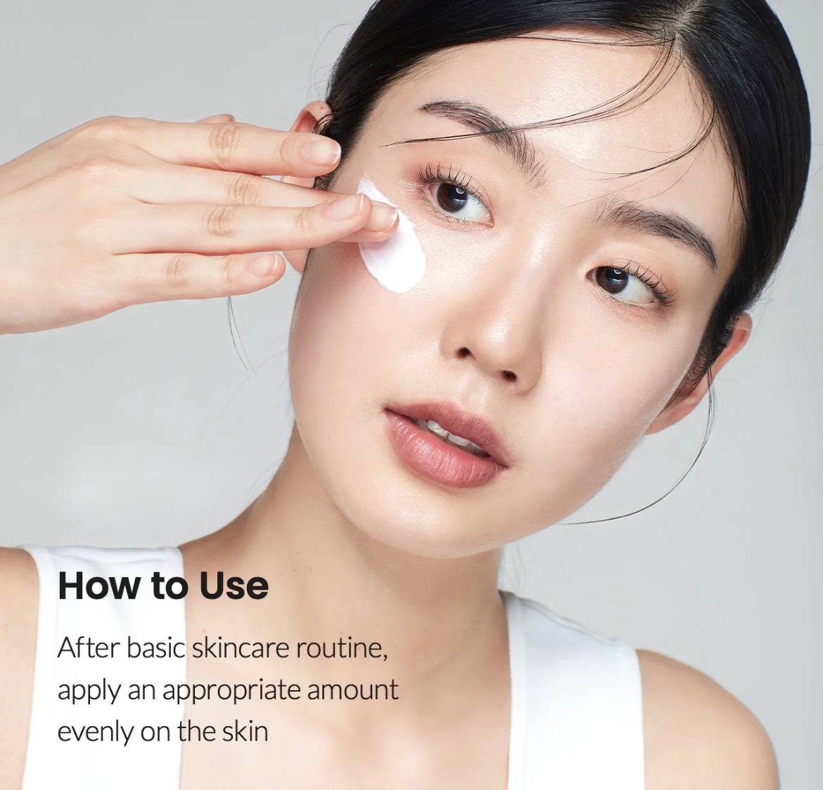 Дівчина азіатської зовнішності наносить білий крем під око, легким рухом пальця