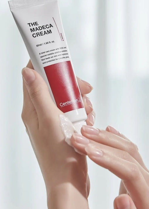 Одна рука тримає тюбик крему Centellian24 The Madeca Cream 50 мл, інша — ніжно наносить крем на шкіру руки